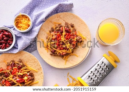 Plates with tasty tacos and glass of juice on color background