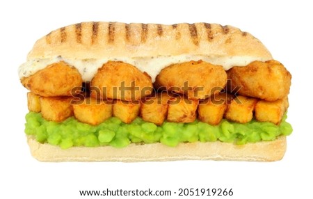 Fish and chips sandwich with battered cod fish and mushy peas in a panini bread roll isolated on a white background