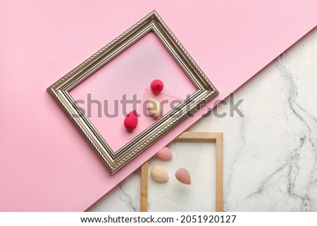 Makeup sponges and frames on color background