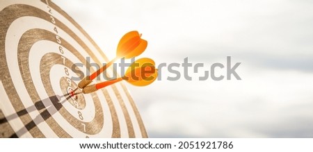 Close up shot red darts arrows in the target  of dartboard center on dark blue sky background. Business target or goal success and winner concept. Royalty-Free Stock Photo #2051921786