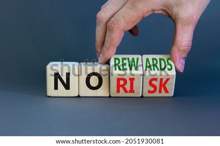 No risk or rewards symbol. Businessman turns wooden cubes and changes words 'no risk' to 'no rewards'. Beautiful grey background. No risk or rewards and business concept. Copy space.