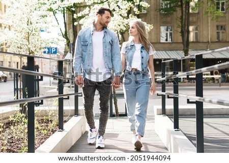 Portrait of young confident and loving couple wearing denim outfits walking during their date on a city street Royalty-Free Stock Photo #2051944094