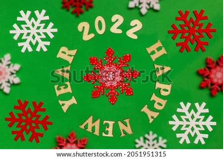 Creative layout with decorative snowflakes and wooden letters on a green background. Greeting card with the phrase Happy New Year 2022. Winter holiday season, Christmas time concept. Flat lay. 