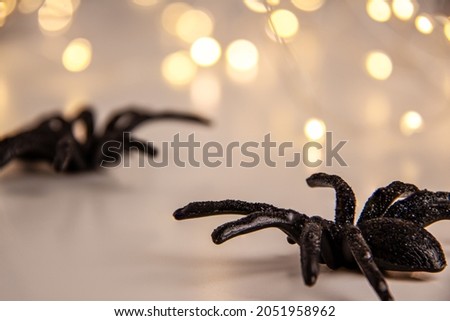 Close up of black horror spiders on bright blurred background with bokeh with copy space. Halloween decoration spooky background concept for holidays