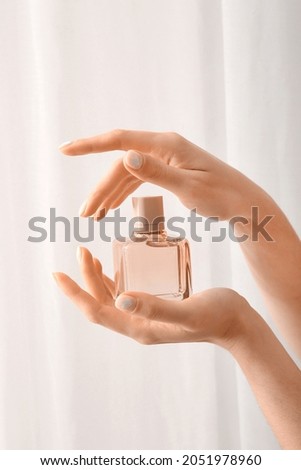 Woman with beautiful manicure holding bottle of perfume on light background Royalty-Free Stock Photo #2051978960