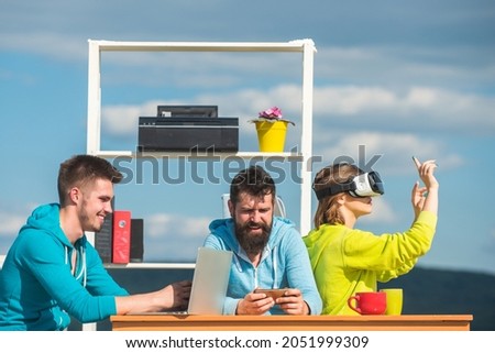 Business team using virtual reality headset and digital gadgets outdoors office meeting. Developers meeting with virtual reality simulator in creative office. Start up team of freelancers.