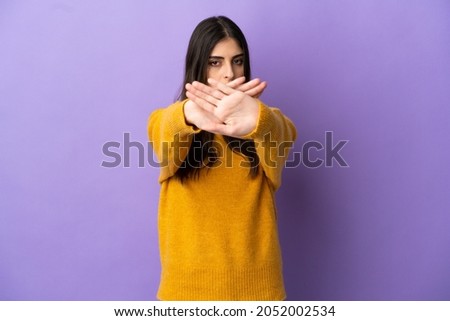 Young caucasian woman isolated on purple background making stop gesture with her hand to stop an act