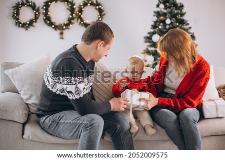 Young family celebrating Christmas and opening present