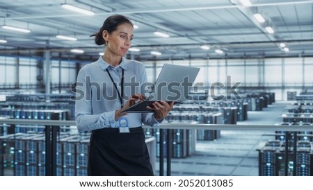 Data Center Engineer Using Laptop Computer. Server Farm Cloud Computing Specialist Facility with Multiethnic Female System Administrator Working with Data Protection Network for Cyber Security. Royalty-Free Stock Photo #2052013085