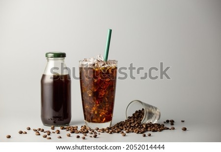 Iced americano coffee with coffee beans on grey background, Black coffee glass package for takeaway. Cold beverage product. Royalty-Free Stock Photo #2052014444