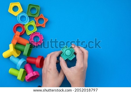 hands collect educational constructor for children, nuts and bolts in the form of geometric shapes