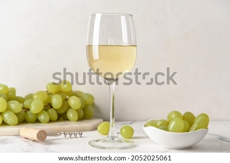 Glass of tasty white wine on white background