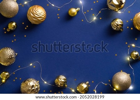 Christmas frame with golden decorations, baubles, garland, confetti on blue background. Christmas holiday celebration, winter, New Year concept. Christmas postcard template, New year banner design.