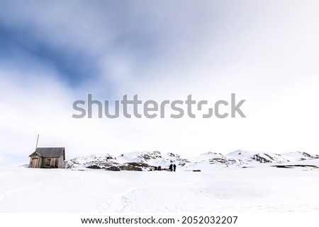 Abandoned cabin and marble mine at Camp Mansfield, New London, Svalbard. Snowy mountain scene with photographers capturing the landscape. 