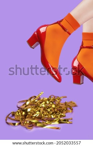 A woman's legs in a red shoe and an orange socks on a 
purple background. The concept of the holiday, parties. Front view
