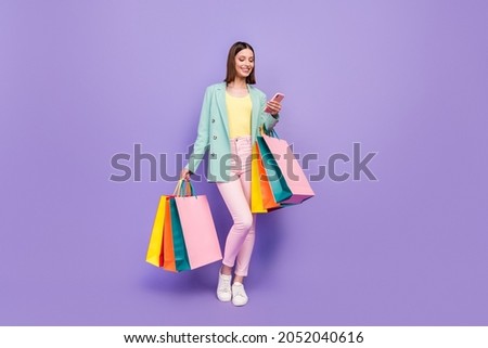 Full length photo of pretty positive lady hold store mall packages use telephone isolated on purple color background