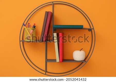 Shelf with books on color background