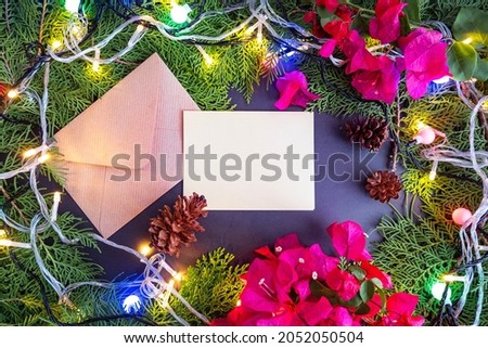 Christmas Background Minimalist Concept. Christmas Greeting Cards With Spruce Leaves, Fir Flowers, Paper Flowers (Bougainvillea) and Christmas Lights. Christmas ideas, winter, Flat lay, top view
