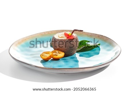 Creative summer dessert isolated on white background. Coconut from chocolate with mousse and passion fruit jelly. Coconut  and passion fruit cake in Hawaiian style. Dessert  in cocktail style