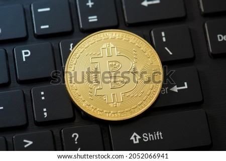 Closeup photo of gold coin with bitcoin symbol on black keyboard background