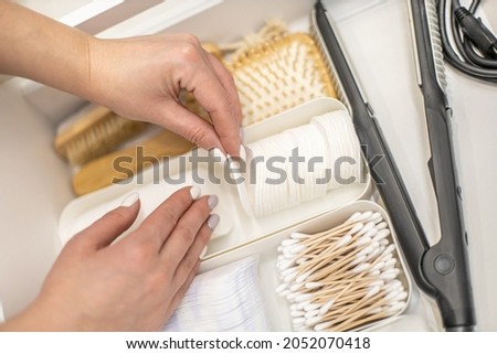 Woman hands organizing vanity drawer and neatly putting organic toiletries of cotton rounds with bamboo buds in muji polypropylene boxes. Zero waste organic toiletries and reusable makeup remover pads Royalty-Free Stock Photo #2052070418