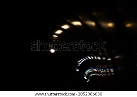 Reflection of dim light in a sparkling transparent surface. The game of reflections of electric light in the tunnel. Abstract photo of night lights in the city.