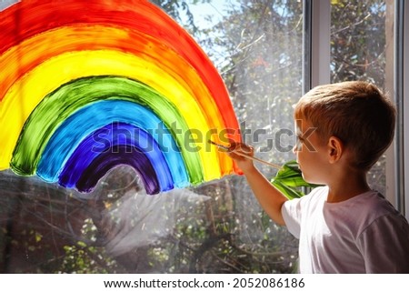 Child at home draws a rainbow on the window. Flash mob society community on self-isolation quarantine pandemic coronavirus. Children create artist paints creativity vacation. Let's all be well