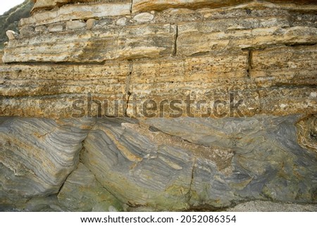 Jurassic sandstones have overlain mudstones in an unconformity in strata exposed along the Dinosaur Coast. Tilting of the older strata and the subsequent layering of the sandstone creates this feature Royalty-Free Stock Photo #2052086354