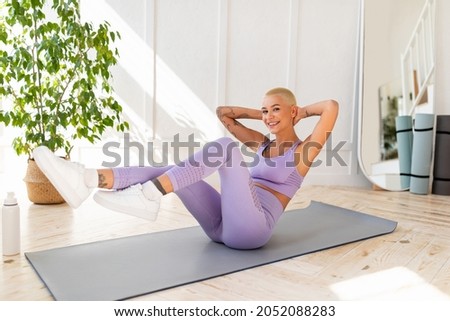 Sporty lady doing fitness on sports mat at home, exercising her abs muscles and smiling to camera, copy space. Young fit woman strengthening her body, leading active lifestyle