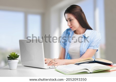 Focused female adult student using laptop, attending online lesson,