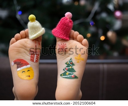 two children's bare feet in small caps on the toes with painted pictures on the New Year's theme. Merry Christmas celebration concept. positive festive cozy Christmas atmosphere