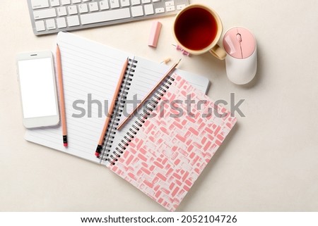 Stationery supplies, modern gadgets and cup of tea on light background