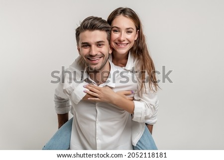 Image of lovely couple having fun while man piggybacking his girlfriend isolated over white background