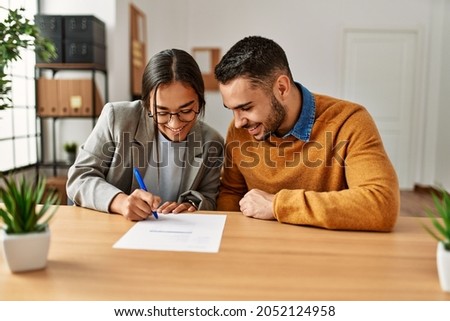 Couple smiling happy reading document at the office.