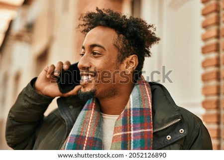 Young african american man smiling happy talking on the smartphone at the city