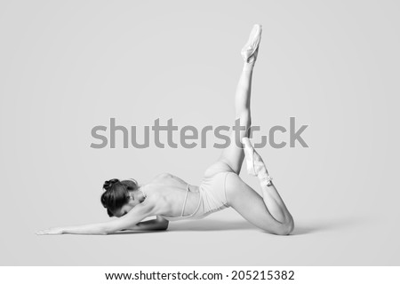 Young and beautiful dancer posing in studio at gray background