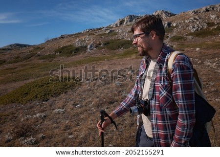 Young cheerful man photographer taking photographs with digital camera in mountains. Travel and active lifestyle concept.