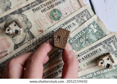 Hand holding miniature house on Dollar money background