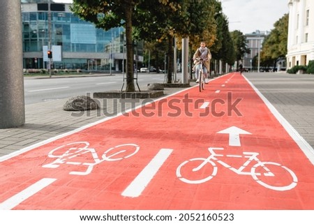 traffic, city transport and people concept - woman cycling along red bike lane with signs of bicycles and two way arrows on street Royalty-Free Stock Photo #2052160523