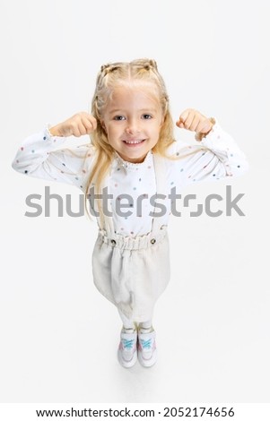 Funny child. Charming cute caucasian little girl posing isolated over white background. Looks happy, cheerful. Childhood, family, happiness, education, facial expression concept, ad