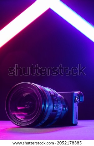 Professional videographer equipment, digital camera with lens. Front view on a black table background.

