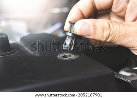Mechanic hand installing automotive plastic fasteners to the car body in the auto repair garage Royalty-Free Stock Photo #2052187901