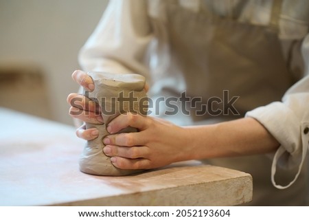 Close up of female hands molding the shape of a pot