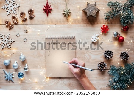 A notebook with New Year resolutions on Christmas wooden background with copy space and Christmas lights bokeh