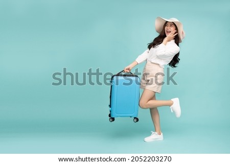 Happy Asian woman traveler standing and holding suitcase isolated on green background, Tourist girl having cheerful holiday trip concept, Full body composition Royalty-Free Stock Photo #2052203270