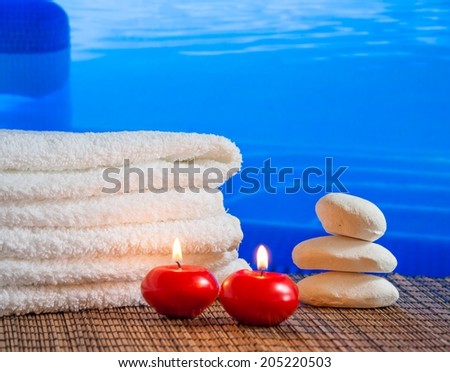 Spa massage border background with towel stacked,red candles and stone on swimming pool background