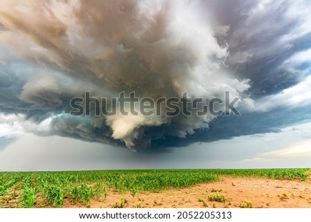 Panorama of a massive mesocyclone weather supercell, which is a pre-tornado stage, passes over a grassy part of the Great Plains while fiercely trying to form a tornado. Royalty-Free Stock Photo #2052205313