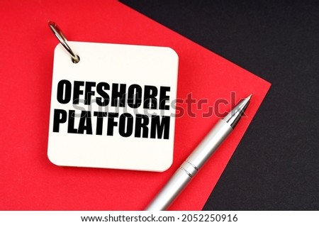 Industry and business concept. On a black and red background lies a pen and a notebook with the inscription - Offshore Platform