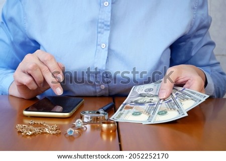 Pawn shop worker verify jewellery and photo or video camera and give money. Customers Buy and Sell Precious Metals, Jewels, Ancient Coins and Second Hand Electric Appliances. Closeup Royalty-Free Stock Photo #2052252170