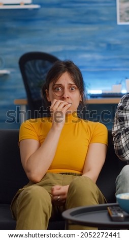 POV of shocked interracial couple watching scary movie on television at home. Multi ethnic husband and wife being afraid and covering eyes while looking at camera in living room Royalty-Free Stock Photo #2052272441